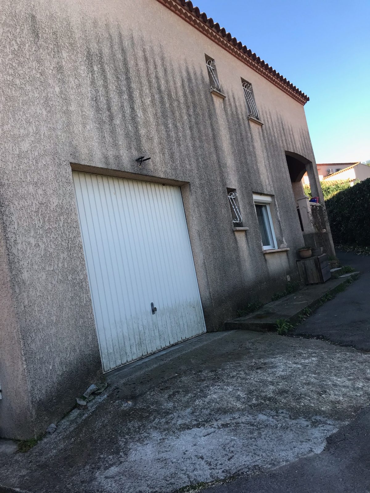 Façade de garage grise, striée de coulures noires avant nettoyage